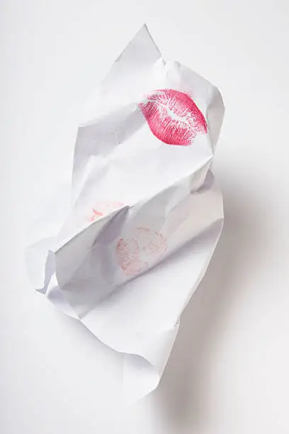 red lip-print on a white, crumpled paper on white
