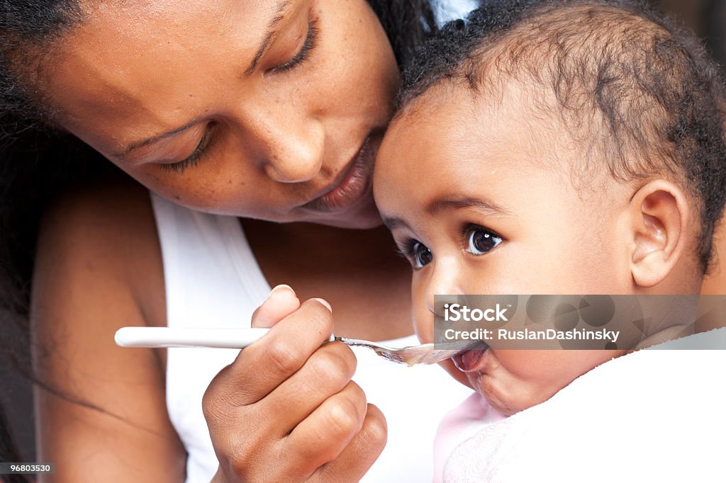 Mother feeding her baby Mother feeding her 5 month old baby with a spoon. Baby - Human Age Stock Photo