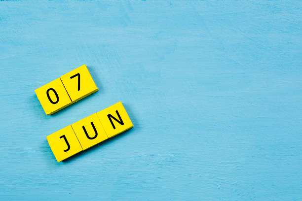 le 7 juin, calendrier cube jaune sur une surface en bois bleue avec espace copie - 7 week old photos et images de collection