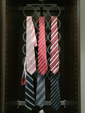 necktie hanging on rack hang line in built-in cupboard.A row of colorful clothes hanging on the rack
