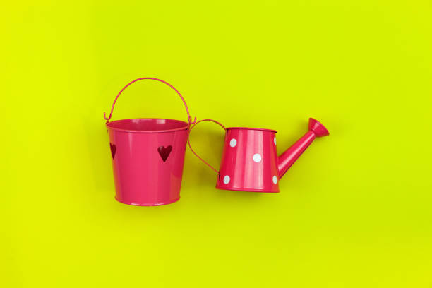 istock Pink watering can isolated on a yellow background. 968100246