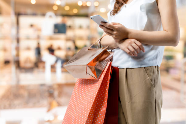 購物的概念。女人提著購物袋使用智慧手機。 - 商店 圖片 個照片及圖片檔