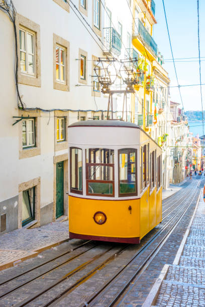 lisboa, portugal. un histórico tranvía amarillo clásico de lisboa construido parcialmente de madera y está asegurado por cable mientras navega a través de las empinadas y estrechas calles de lisboa antigua - cable car lisbon portugal portugal old fotografías e imágenes de stock