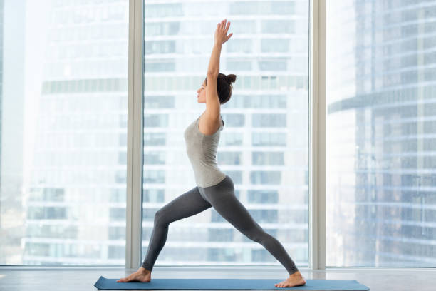 Young sporty woman doing Virabhadrasana 1 exercise