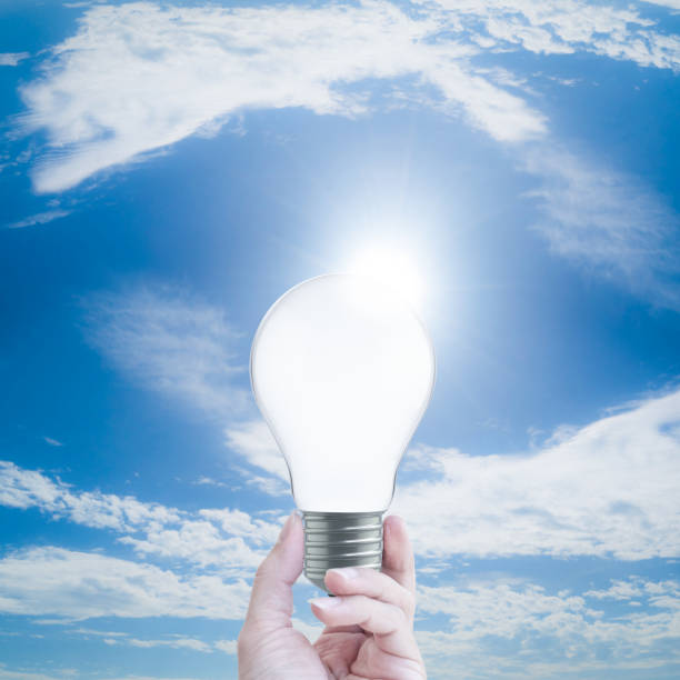 istock hand holding a light bulb on blue sky background  with clipping path 968197242