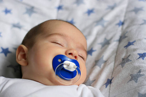 Sleeping baby with a blue pacifier stock photo