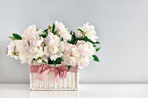 Peonies in white rustic basket, wedding card or Mother's Day concept.