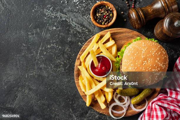 Burger And Fries On Wooden Board On Dark Stone Background Stock Photo - Download Image Now