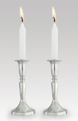 Low-key studio shot of elegant advent candles with two flames in the foreground, black background with defocused flames