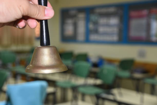 A hand holding a bell in a school stock photo