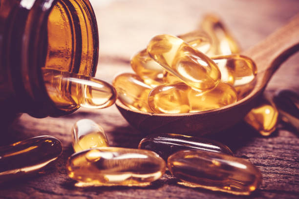 비타민 d와 오메가 3 생선 기름 캡슐 보충에 좋은 뇌, 심장 및 건강 혜택을 먹는 나무 접시를 닫습니다 - vitamin d capsule fish oil yellow 뉴스 사진 이미지