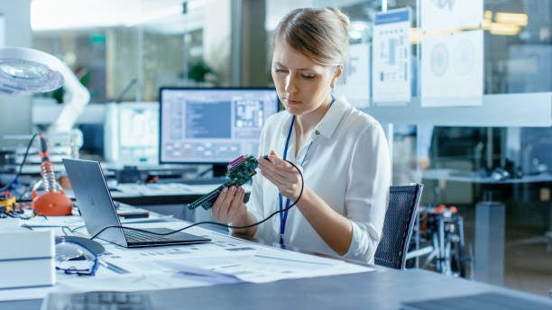 istock Female Computer Scientists Connects Circuit Board to Her Laptop and Starts Programming it. She Works in the Technologically Advanced Laboratory. 968289526