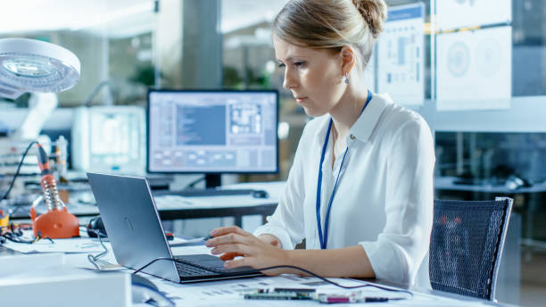 istock Female Computer Scientists Connects Circuit Board to Her Laptop and Starts Programming it. She Works in the Technologically Advanced Laboratory. 968289546