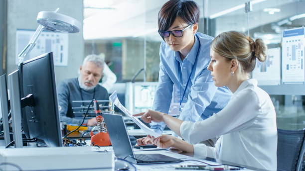 istock Female Computer Scientists Connects Circuit Board to Her Laptop with Mock-up Green Screen. She Works in the Technologically Advanced Laboratory. 968289548