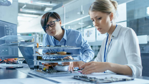 istock Two Computer Engineers Choose Printed Circuit Boards to Work with. In The Background Technologically Advanced Scientific Research Center. 968289554