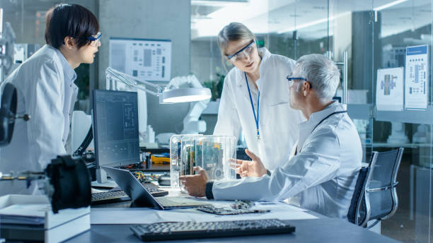 istock Team of Scientists Choose Between Printed Circuit Board to Work With. In The Background Technologically Advanced Scientific Research Center. 968289606
