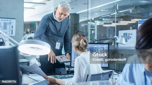 Electronics Engineer Works With Robot Manipulating Its Responses Laptop Computer Senior Engineers Talks With Chief Programmer Computer Science Research Laboratory With Specialists Working Stock Photo - Download Image Now