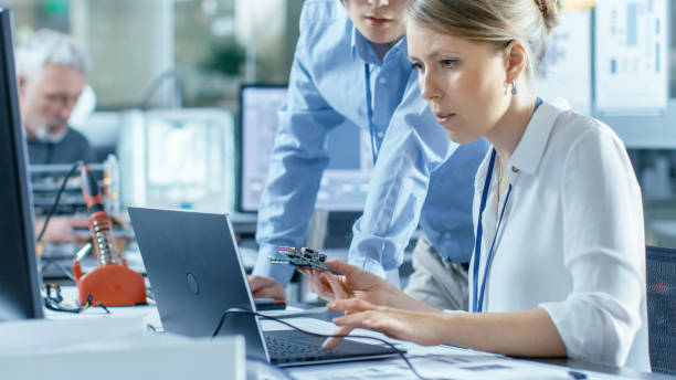 istock Female Computer Scientists Connects Circuit Board to Her Laptop and Starts Programming it. She Works in the Technologically Advanced Laboratory. 968289798