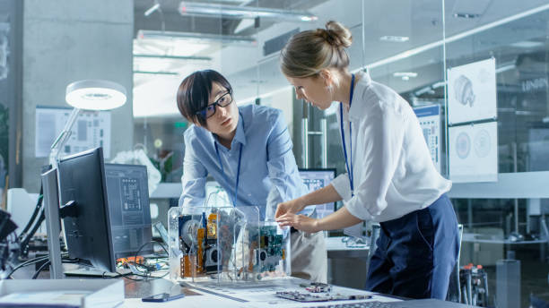 istock Two Computer Engineers Choose Printed Circuit Boards to Work with. In The Background Technologically Advanced Scientific Research Center. 968289842