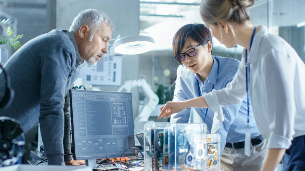 istock Team of Computer Engineers Choose Printed Circuit Boards to Work with, Computer Shows Programming in Progress. In The Background Technologically Advanced Scientific Research Center. 968289868
