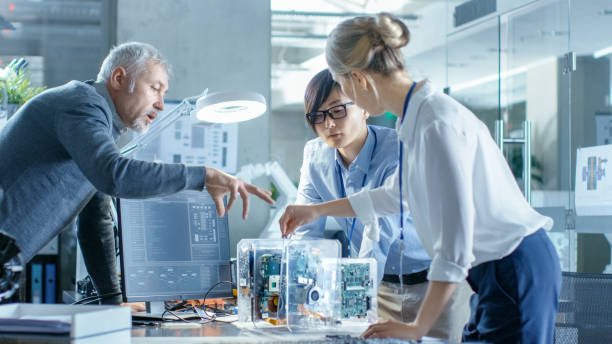istock Team of Computer Engineers Choose Printed Circuit Boards to Work with, Computer Shows Programming in Progress. In The Background Technologically Advanced Scientific Research Center. 968289876