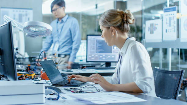 istock Female Computer Scientists Connects Circuit Board to Her Laptop with Mock-up Green Screen. She Works in the Technologically Advanced Laboratory. 968303210