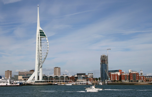 DSLR Photo of the Spinnaker Tower, Portsmouth, with Gunwharf Quays in the background and boats crossing Portsmouth Harbour in the foreground and the Isle of Wight ferry at its berth.
