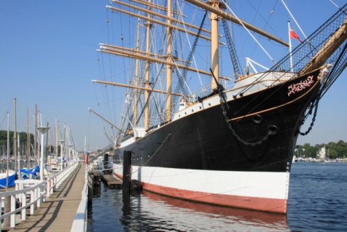 Old VOC sailing ship Halve Maen at the river IJssel during the 2018 Sail Kampen event in the Hanseatic league city of Kampen in Overijssel, The Netherlands. The Halve Maen was a trading ship of the Dutch East India Company (Dutch: Verenigde Oost-Indische Compagnie or VOC) and sailed into what is now New York Harbor in September 1609 during a search for a western passage to China. People on board are looking at the view and a crownd on the quay is watching the ships.