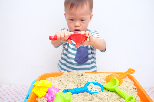 Cute little Asian 18 months / 1 year old toddler boy playing with kinetic sand at home ,Fine motor skills development, Montessori education, Creative play for kids concept - Selective focus at hands