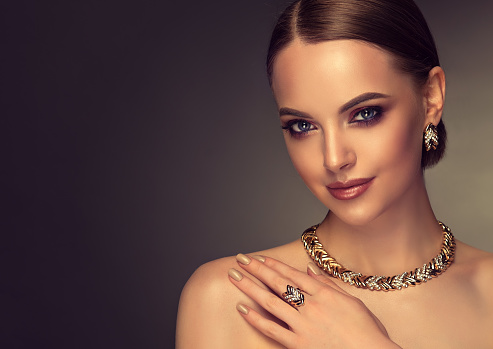 Bonito modelo con estilo de maquillaje de ojos ahumados está demostrando joyas doradas. photo