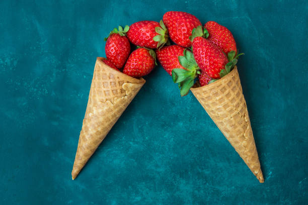 istock Ripe organic strawberries in ice cream cones on dark blue background. Creative conceptual image 968316224