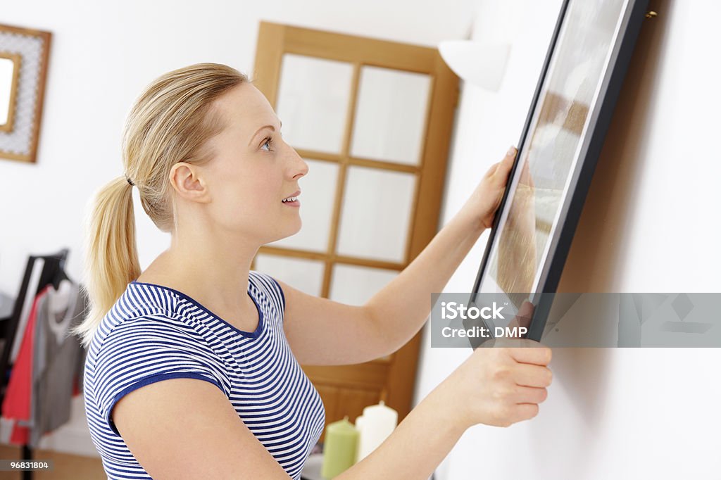close-up of young attractive woman hanging picture on a wall  Hanging Stock Photo