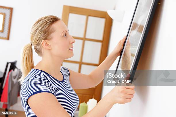 Closeup Of Young Attractive Woman Hanging Picture On A Wall Stock Photo - Download Image Now
