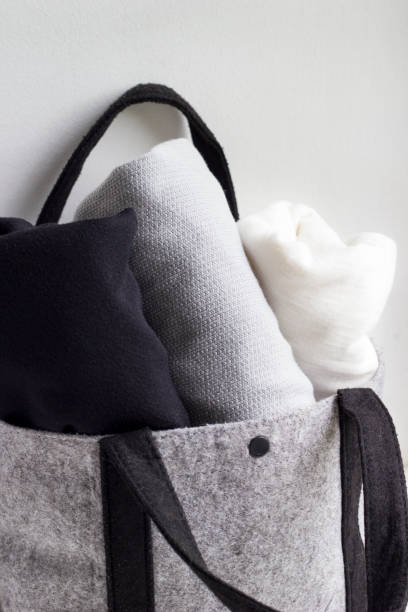 istock Close-up rolled clothes in woolen gray bag on white background. 968318702