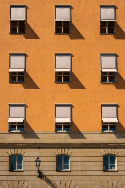 vorderansicht des viele symmetrische fenster mit sonnenstoren auf einem steinernen stadt gebäude. - apartment window sky sun stock-fotos und bilder