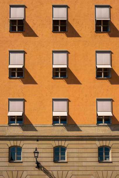 Front view of many symmetrical windows with sun blinds on a stone city building. stock photo