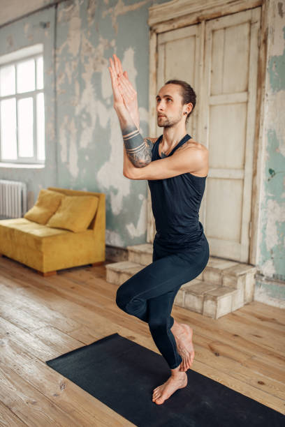 istock Male yoga doing balance exercise on mat in gym 968326076