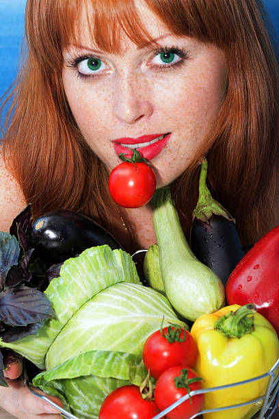 girl holds by teeth a small tomato stock photo