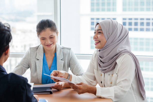 istock Business Women distrubuting project documents to the atendees 968347276
