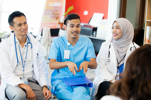 Group of medical students in a classroom in a hospital studying for their medical degree. They are at a healthcare facility in Newcastle Upon Tyne, North East England. The students are all wearing their student nurse uniforms, working together as a team, discussing together. They are using laptops.