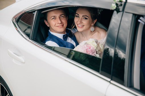 A man and a woman are hugging in the back seat of the car. Portrait of lovers looking at the open window of the car and smiling