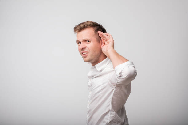istock A young man puts a hand on the ear try to hear the whisper, isolated on a white background. 968383656