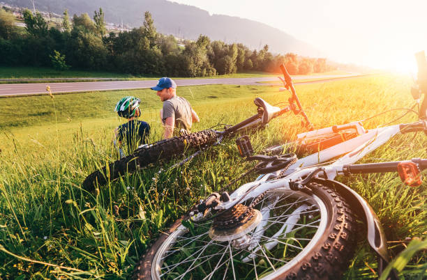 padre e figlio si rilassano in erba verde aftwr bicykle passeggiata - cycling teenager action sport foto e immagini stock