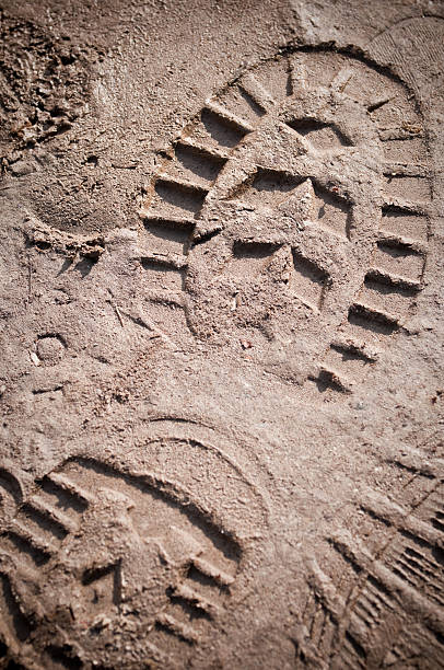 A boot print in the mud close-up Heavy footprint left on a muddy sand by a male boot. shoe print stock pictures, royalty-free photos & images