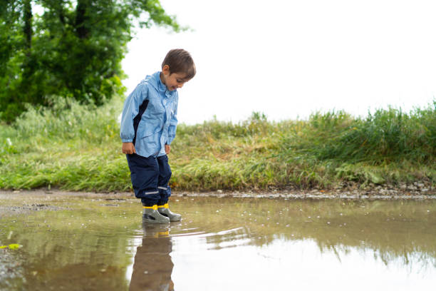 istock four years old boy standing in rain puddle 968397612