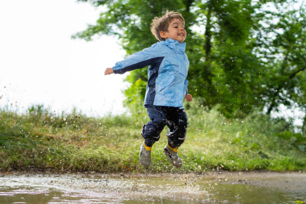 istock happy little boy jumping in dirty rain puddle 968397648