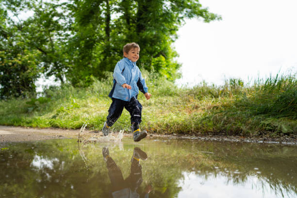 istock smilling little boy running through rain puddle 968397656