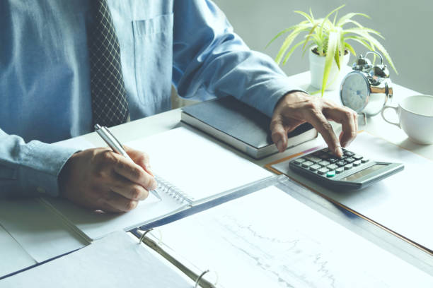 istock business man work writing document and putting calculator on table in office for finance,accounting concept. 968422400