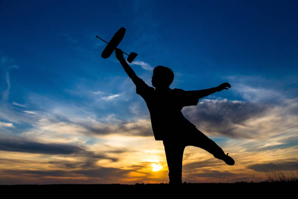 istock Silhouette of boy with his airplane against sunset 968445544