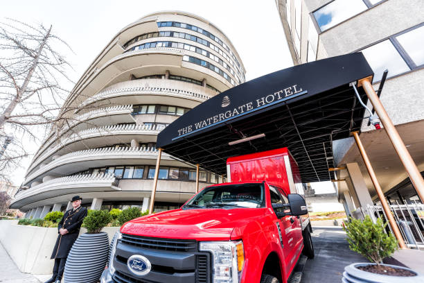 Watergate hotel sign building in capital city, red truck, porter, doorman, security guard in winter coat and hat, residential building closeup Washington DC, USA - April 5, 2018: Watergate hotel sign building in capital city, red truck, porter, doorman, security guard in winter coat and hat, residential building closeup hotel watergate stock pictures, royalty-free photos & images